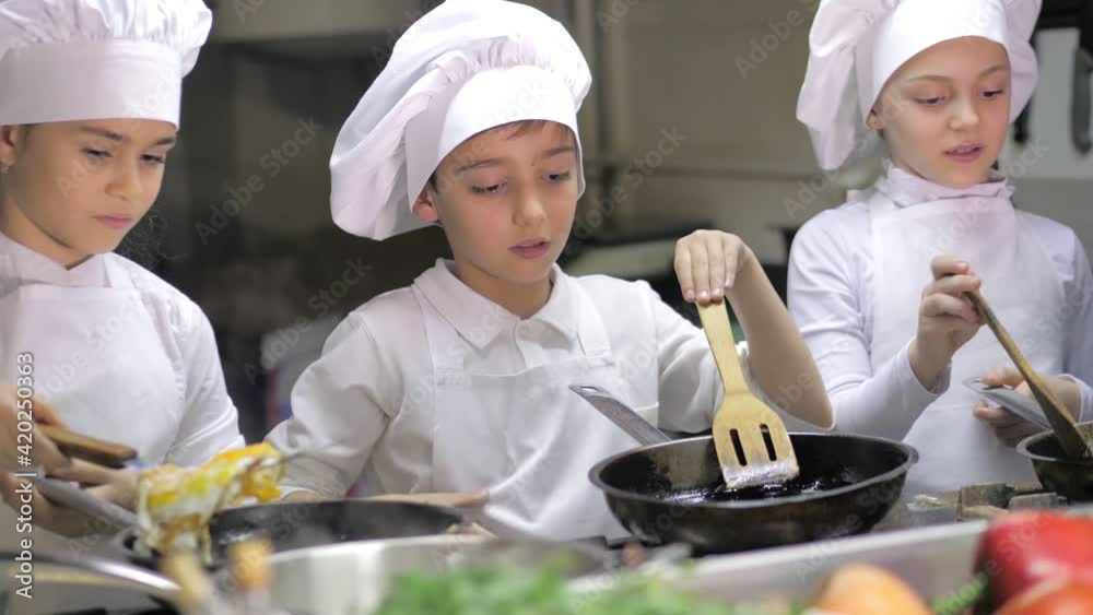 Kids learning how to cook eggs in a cooking class in restaurant kitchen Kids learning how to cook eggs in a cooking class in restaurant kitchen