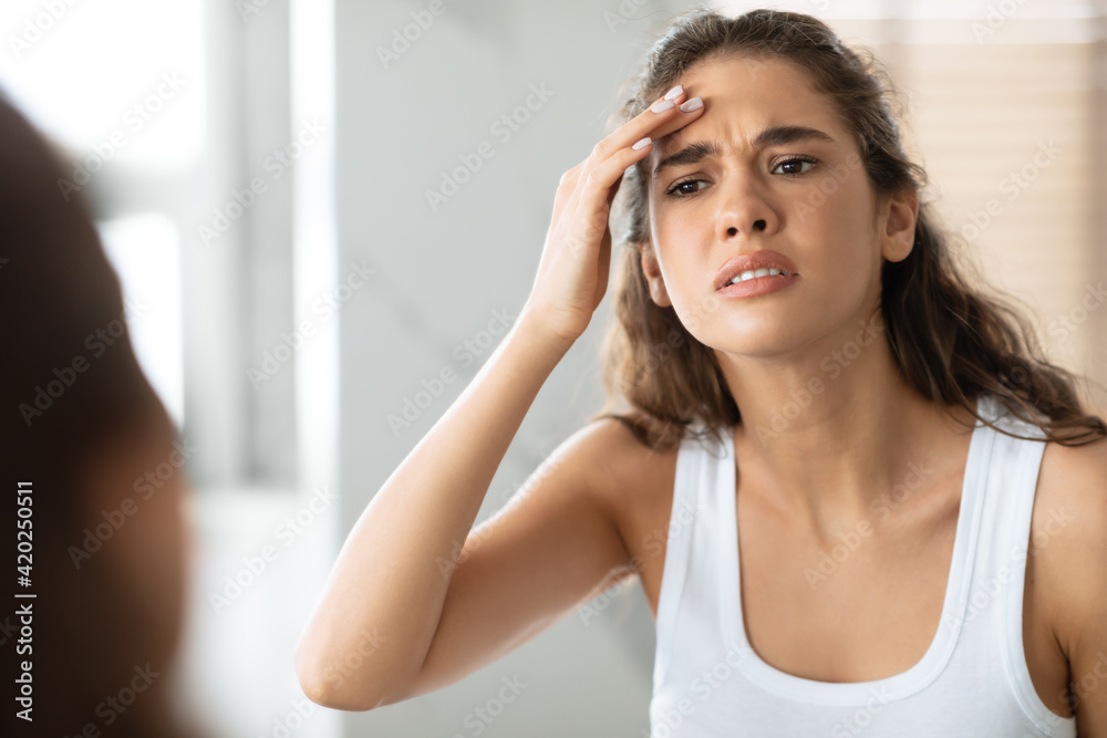 Concerned Woman Searching Wrinkles Looking At Forehead In Bathroom Indoor Concerned Woman Searching Wrinkles Looking At Forehead In Bathroom Indoor