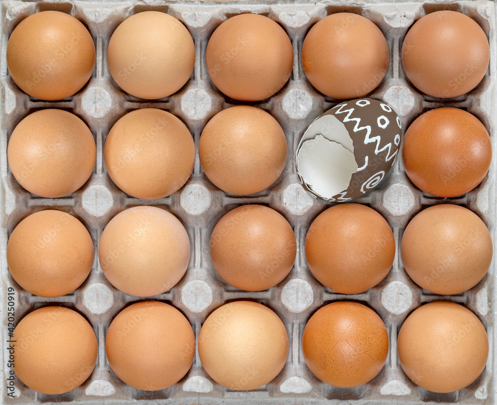 Easter eggs. Celebration Easter. Eggs in carton. Eggs in box. Healthy Farm Food in eco packaging. One broken colorful easter egg among the raw, unpainted eggs. Holiday easter decoration. Easter eggs. Celebration Easter. Eggs in carton. Eggs in box. Healthy Farm Food in eco packaging. One broken colorful easter egg among the raw, unpainted eggs. Holiday easter decoration.