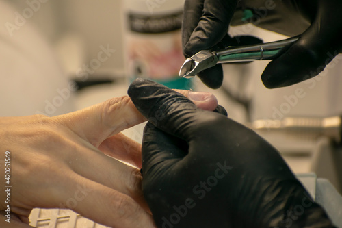 The master processes the client's nails with scissors. Nail salon.