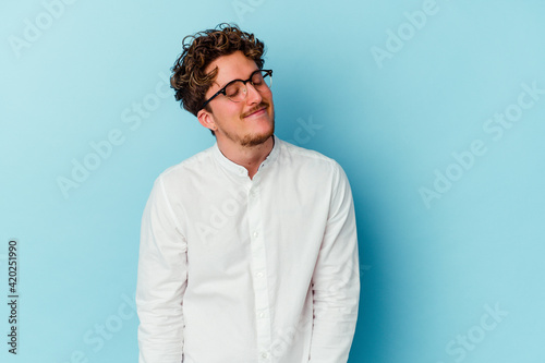 Young caucasian business man isolated on blue background dreaming of achieving goals and purposes © Asier