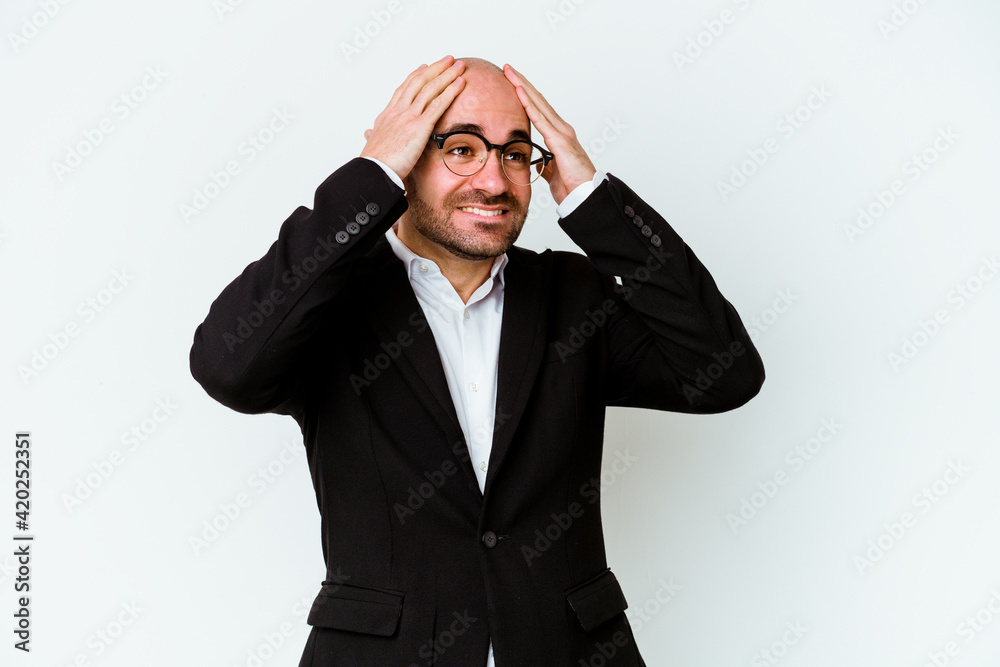 Young business caucasian bald man isolated on blue background laughs joyfully keeping hands on head. Happiness concept. Young business caucasian bald man isolated on blue background laughs joyfully keeping hands on head. Happiness concept.