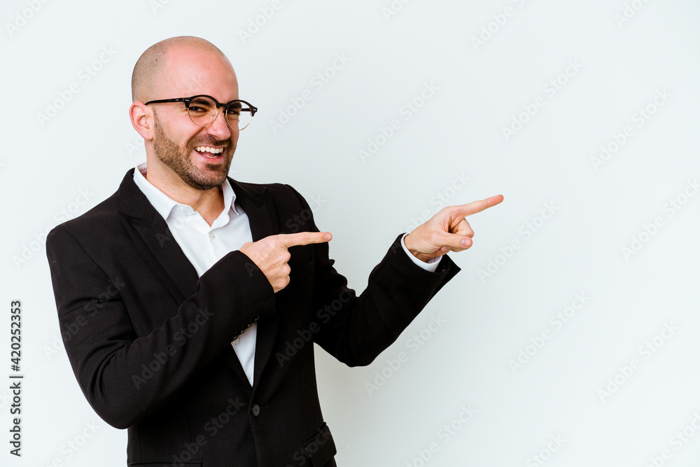 Young business caucasian bald man isolated on blue background excited pointing with forefingers away. Young business caucasian bald man isolated on blue background excited pointing with forefingers away.