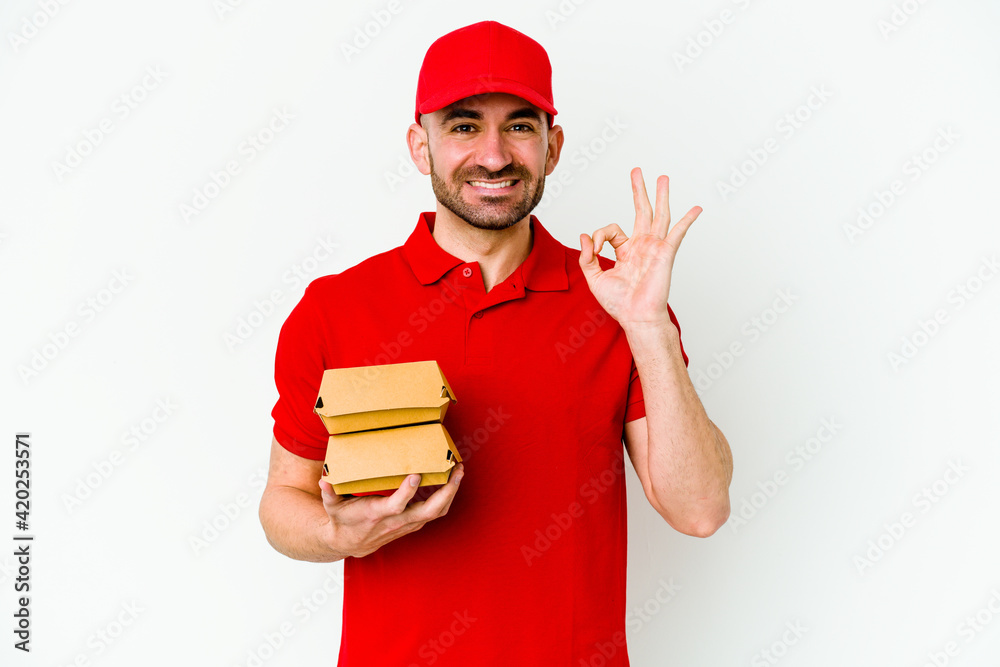 Young caucasian delivery man isolated on white background cheerful and confident showing ok gesture.