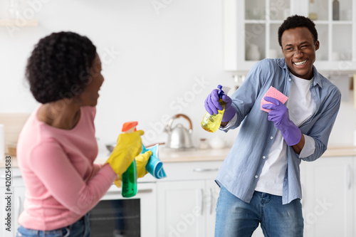 Joyful african american couple shooting with cleaning sprays