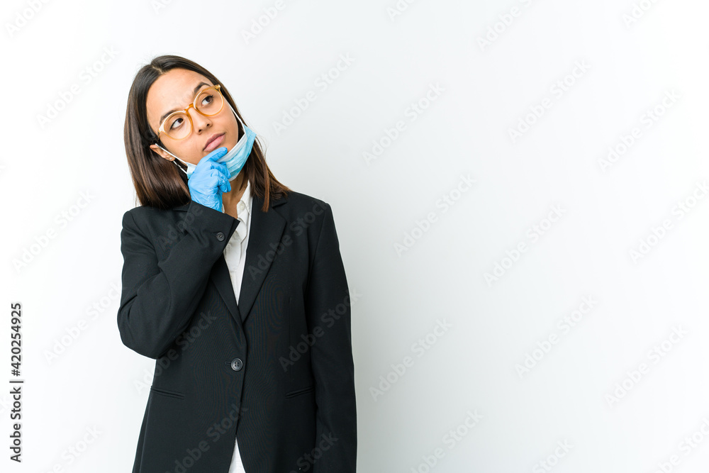 Young business latin woman wearing a mask to protect from covid isolated on white background looking sideways with doubtful and skeptical expression. Young business latin woman wearing a mask to protect from covid isolated on white background looking sideways with doubtful and skeptical expression.