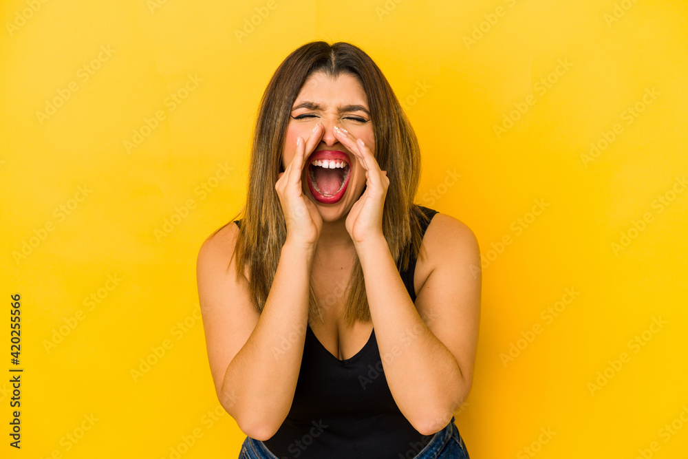 Young indian woman isolated on yellow background shouting excited to front. Young indian woman isolated on yellow background shouting excited to front.