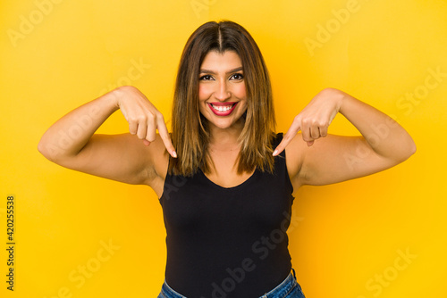 Young indian woman isolated on yellow background points down with fingers, positive feeling.