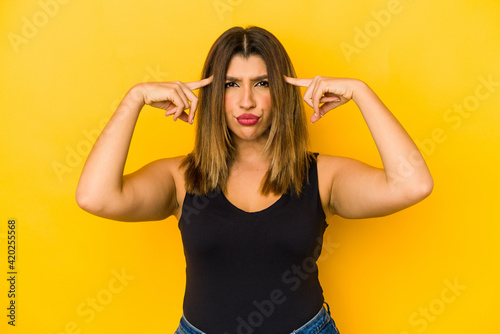 Young indian woman isolated on yellow background focused on a task, keeping forefingers pointing head.