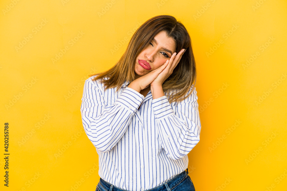 Young indian woman isolated on yellow background yawning showing a tired gesture covering mouth with hand. Young indian woman isolated on yellow background yawning showing a tired gesture covering mouth with hand.