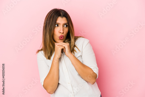 Young indian woman isolated on pink background praying for luck, amazed and opening mouth looking to front.