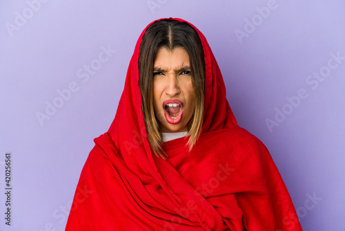 Young indian woman wearing a hijab isolated screaming very angry and aggressive. © Asier