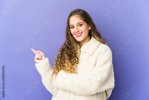 Young caucasian cute woman smiling cheerfully pointing with forefinger away.
