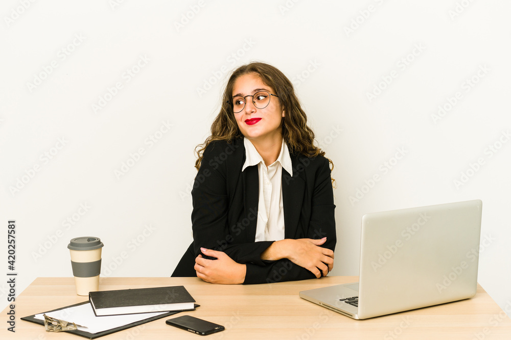 Young caucasian business woman working on her desktop isolated dreaming of achieving goals and purposes Young caucasian business woman working on her desktop isolated dreaming of achieving goals and purposes