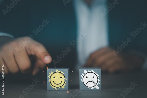 Customer man hand choose smiley face icon on wood cube. Satisfaction concept.