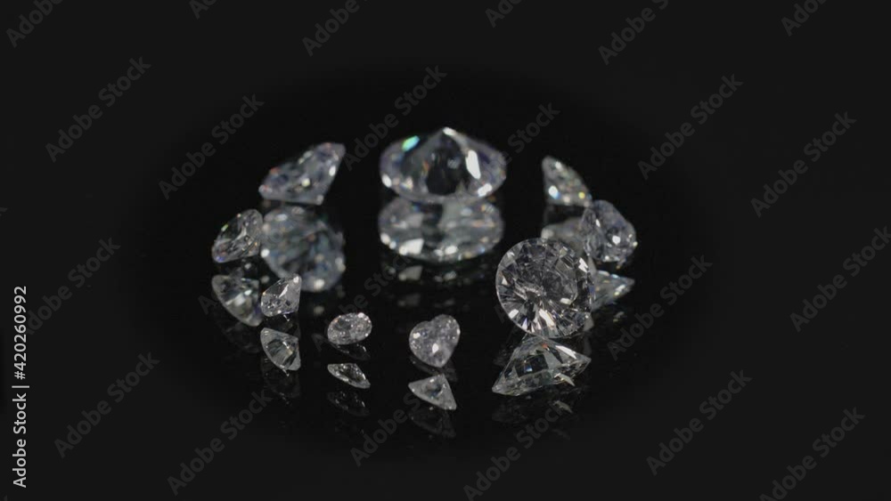 diamonds in different shape and different size place on center of circle on mirror are spinning around in black background. diamonds in different shape and different size place on center of circle on mirror are spinning around in black background.
