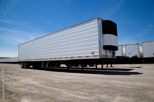Transport truck trailer sitting in yard with a row of trailers behind it photo