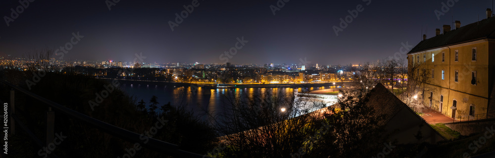 Night panoramic view of Novi Sad, Serbia cityscape with bridges, Danube river and Petrovaradin fortress with beautiful colorful street lights from the town