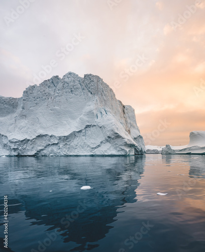 Arctic nature landscape with icebergs in Greenland icefjord with midnight sun sunset sunrise in the horizon. Early morning summer alpenglow during midnight season. Ilulissat, West Greenland. photo