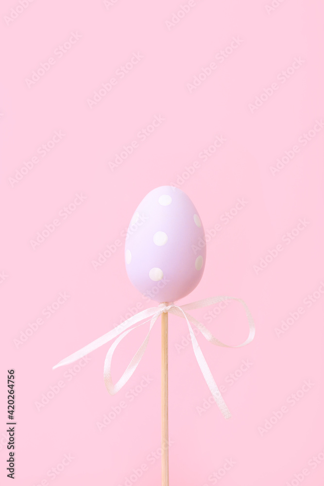 Lilac Easter egg on stick on pink background. Festive Easter holiday greeting card with copy space.