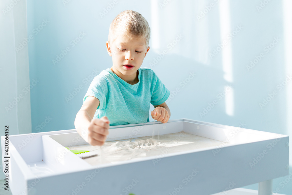 child plays with sand at home on the table, drawing on the sand child plays with sand at home on the table, drawing on the sand