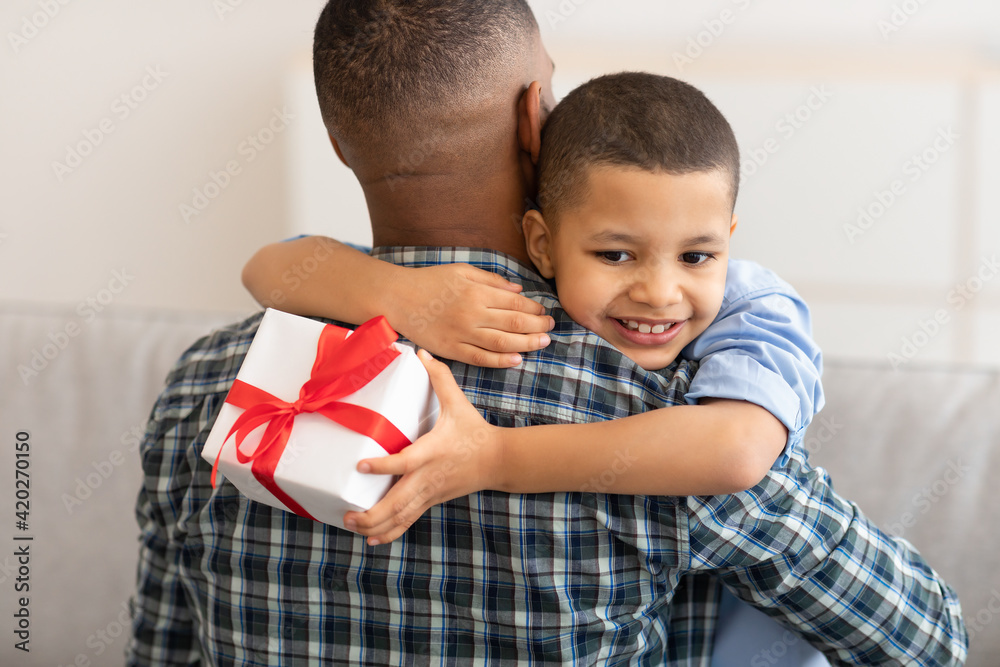 African Little Son Hugging Dad Receiving Birthday Gift At Home African Little Son Hugging Dad Receiving Birthday Gift At Home