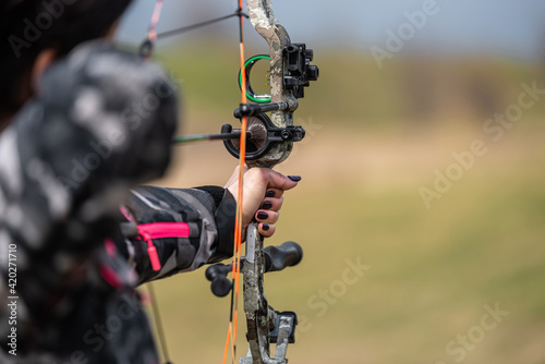 a man in a camouflage suit shoots with a professional bow and arrow, close-up shot