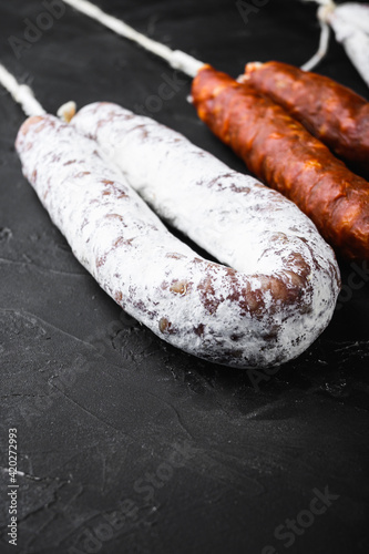 Traditional spanish sausages fuet and chorizo on black surface with copy space
