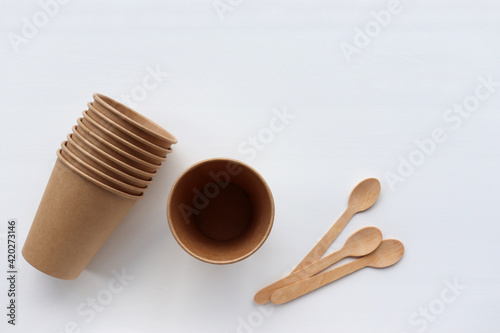 Kraft paper and wooden kitchen utensils on table. Recycled and sustainable products on white background. Zero waste concept. 