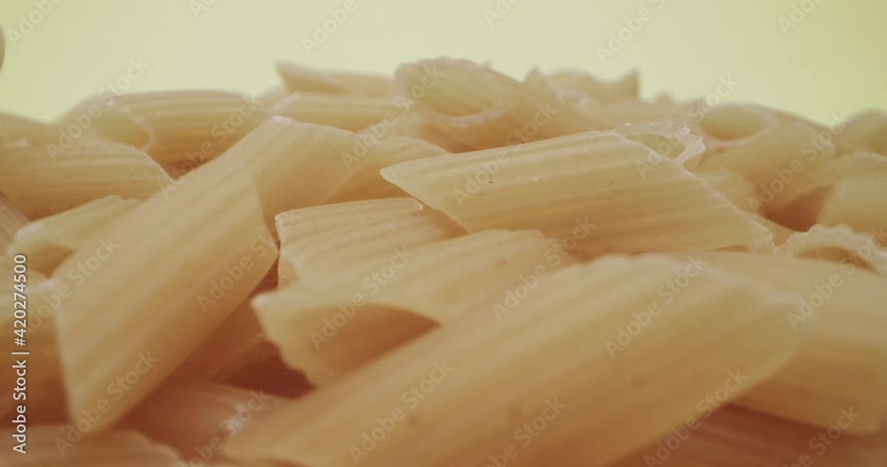 Falling raw half furrowed pens or mezze penne rigate Italian pasta. Close up and dolly in Falling raw half furrowed pens or mezze penne rigate Italian pasta. Close up and dolly in