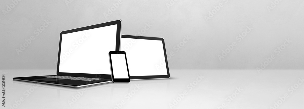 Laptop, mobile phone and digital tablet pc on white concrete office desk. Banner background Laptop, mobile phone and digital tablet pc on white concrete office desk. Banner background