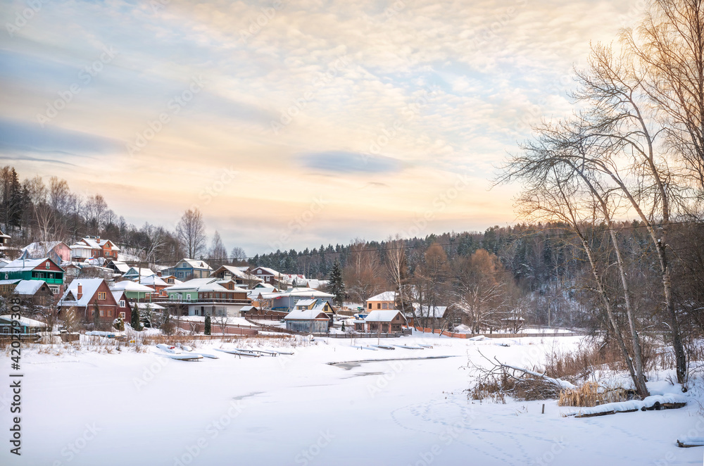 Wooden houses on the banks of the snow-covered Shokhonka River in Plyos