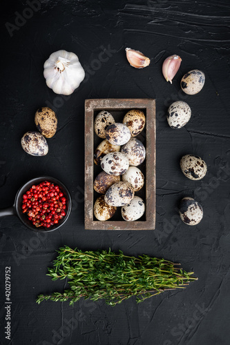 Organic quail eggs, top view, on black textured background