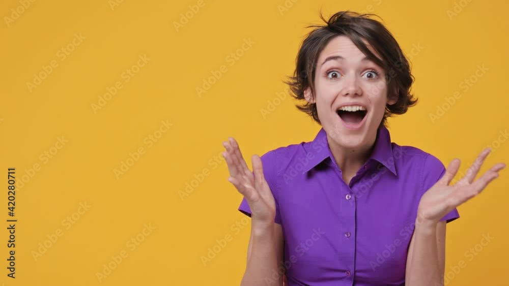 Smiling surprised shocked beautiful short hairdo young woman 20s years old in pink violet shirt looking aside on workspace copy space mockup promo commercial area isolated on yellow background studio Smiling surprised shocked beautiful short hairdo young woman 20s years old in pink violet shirt looking aside on workspace copy space mockup promo commercial area isolated on yellow background studio
