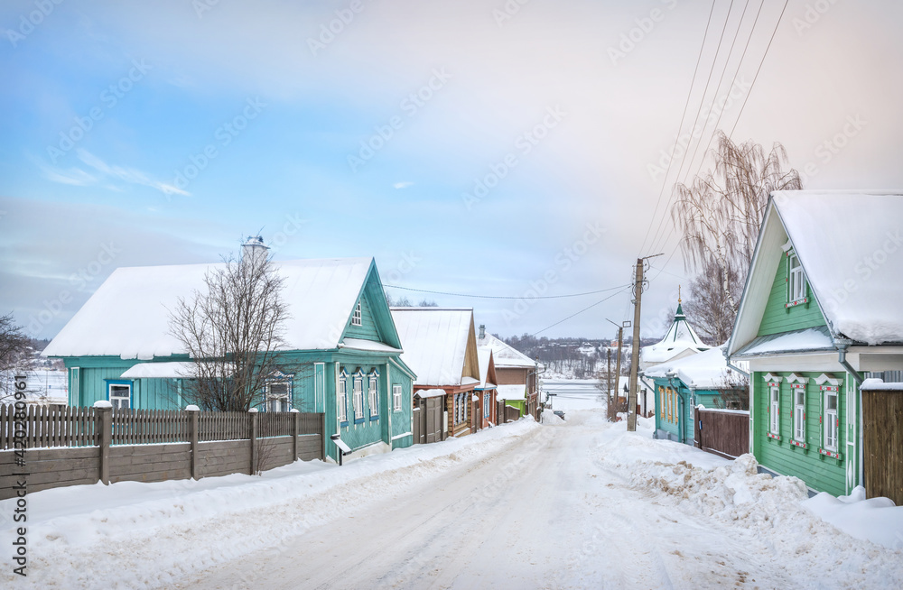 Wooden houses on Nikolskaya Street and a view of the frozen Volga in Plyos Wooden houses on Nikolskaya Street and a view of the frozen Volga in Plyos