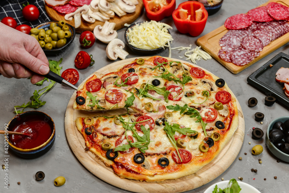 pizza with salami, tomatoes, mushrooms and cheese. ingredients and spices on grey concrete background 