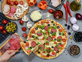 pizza with salami, tomatoes, mushrooms and cheese. ingredients and spices on grey concrete background 
