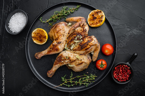 Grilled whole chicken, with chimichurri sauce, on black background, top view