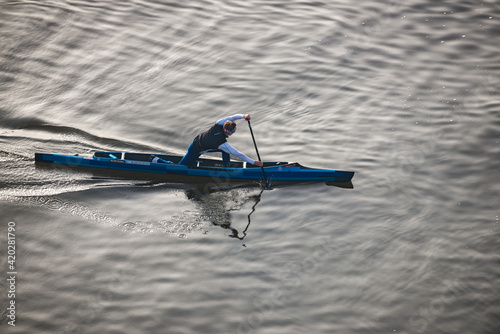 Prague, Czech republic - February 24, 2021. Aerial view of young man sailing on blue single canoe in canoe sprint in sunset photo