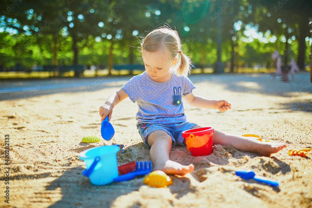 Adorable little girl having fun on playground in sandpit Adorable little girl having fun on playground in sandpit