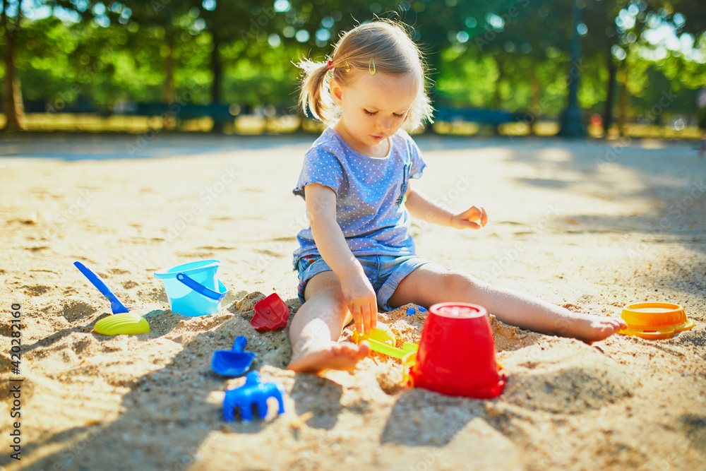 Adorable little girl having fun on playground in sandpit Adorable little girl having fun on playground in sandpit