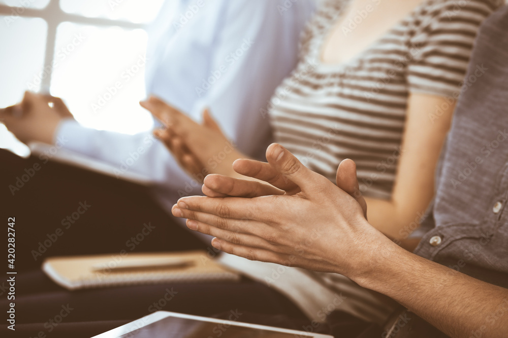 Naklejka premium Business people clapping at meeting or conference, close-up of hands. Group of unknown businessmen and women in modern white office. Success teamwork, corporate coaching and applause concept