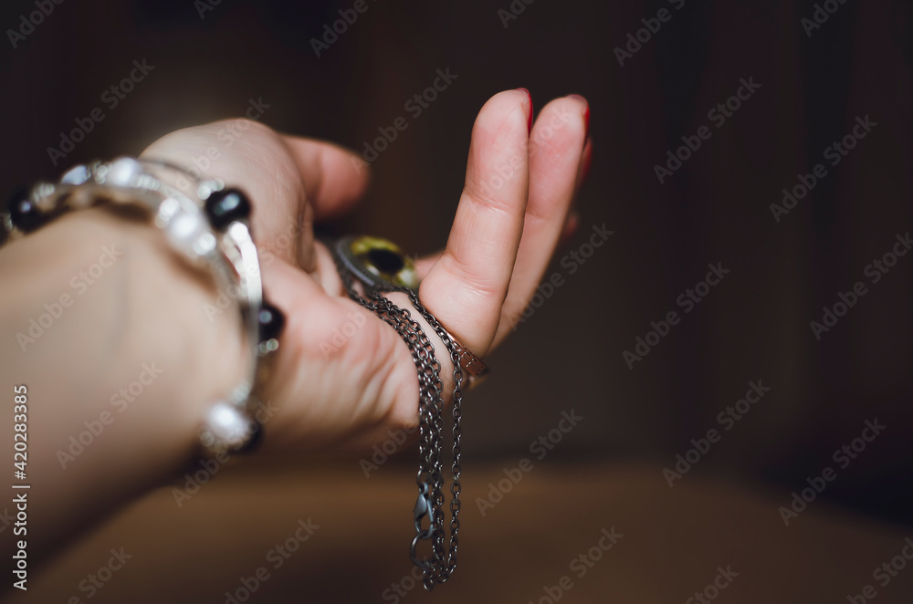 Female hand with jewelry on a dark background.