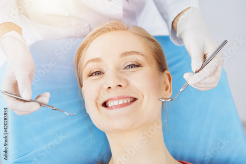 Happy smiling woman is being examined by dentist at dental clinic. Healthy teeth and medicine, stomatology concept