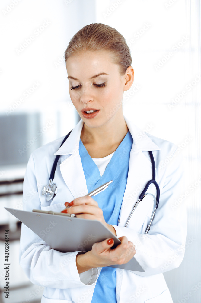 Woman - doctor is using clipboard for filling up medication history record in clinic. Medicine concept Woman - doctor is using clipboard for filling up medication history record in clinic. Medicine concept