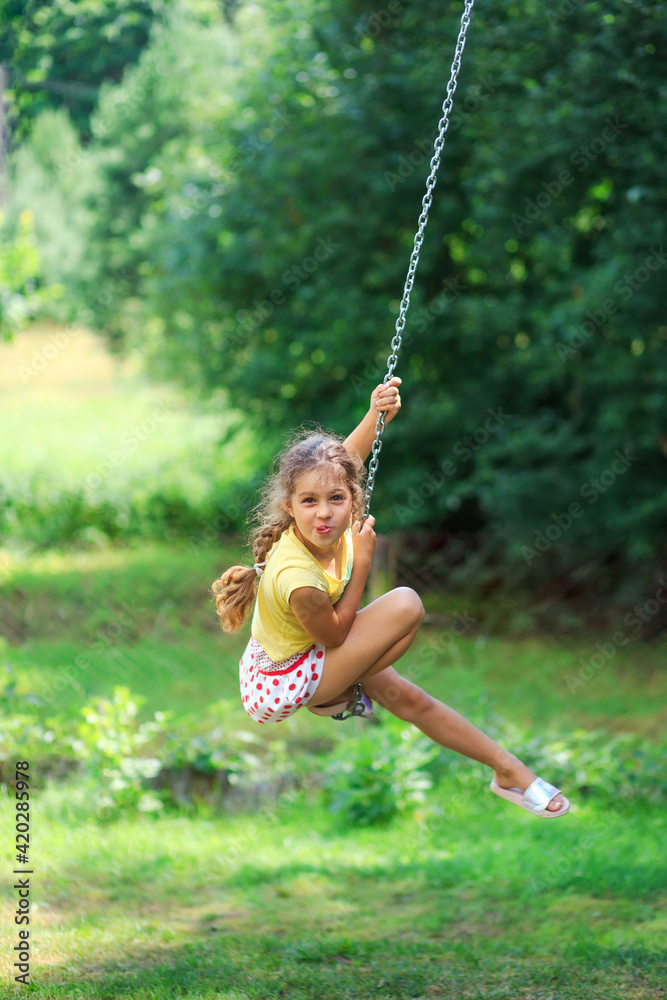 Portrait of Beautiful little girl Is swinging and playing at summer park. Soft focused