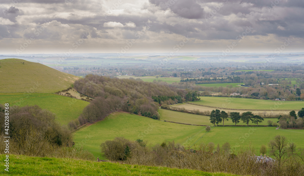 scenic Southerly view over Oare and across the Pewsey Vale valley with green pastures and a cloudy light grey sky