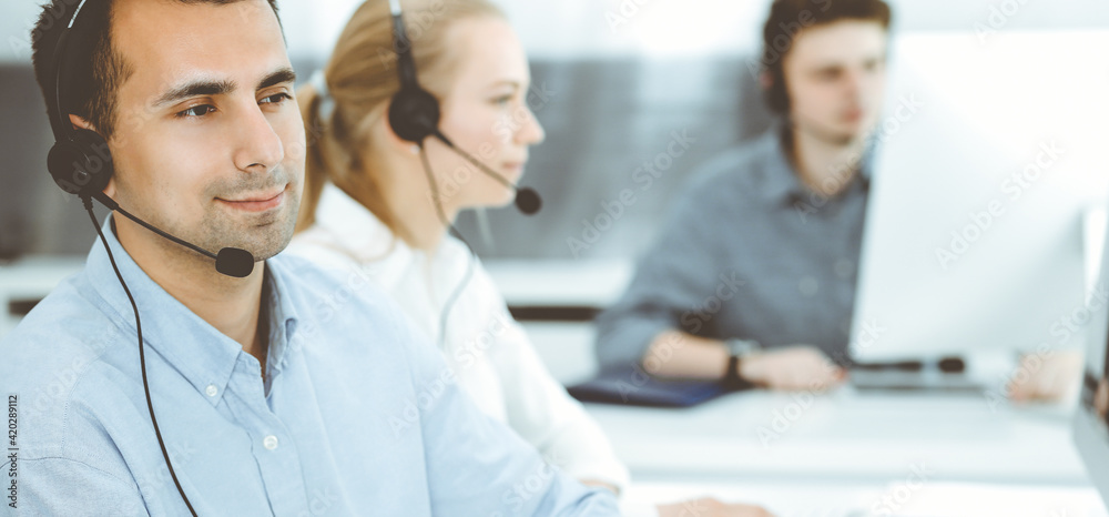 Call center. Group of casual dressed operators at work. Adult businessman in headset at customer service office. Telesales in business Call center. Group of casual dressed operators at work. Adult businessman in headset at customer service office. Telesales in business