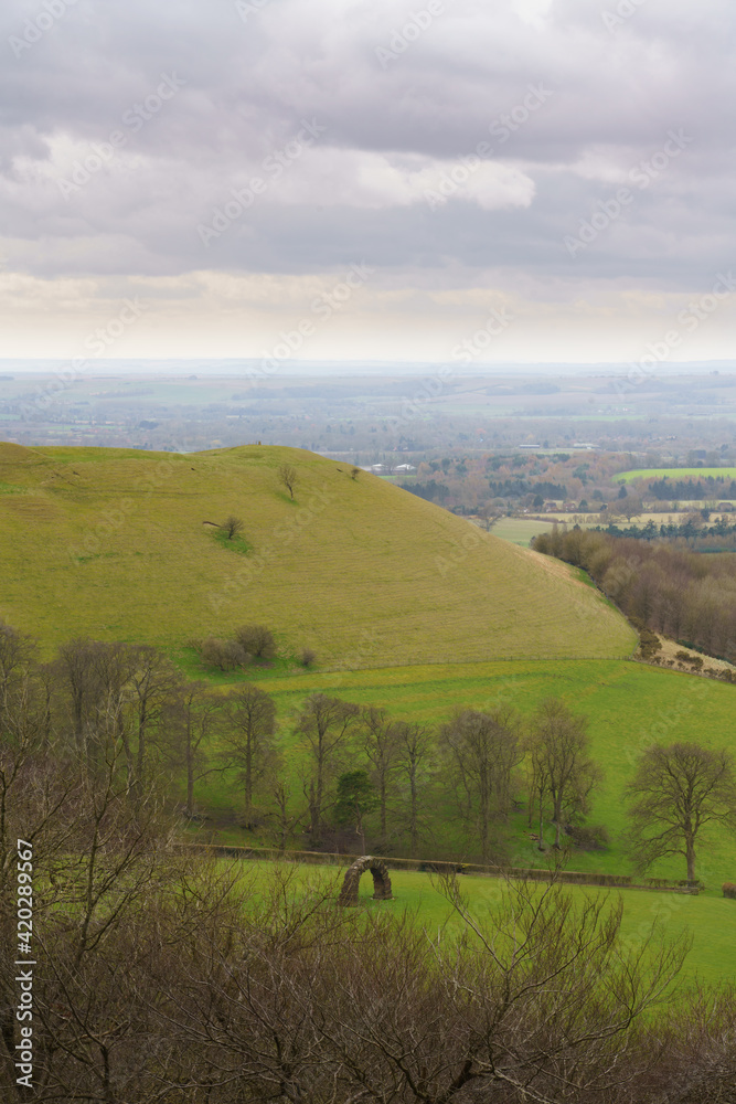 scenic Southerly view over Oare and across the Pewsey Vale valley with green pastures and a cloudy light grey sky