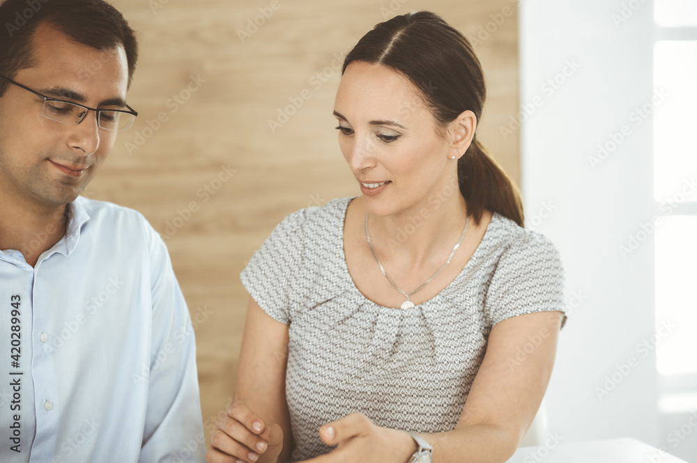 Businessman and hispanic business woman working with computer in a modern office. Group of diverse people. Teamwork, partnership and business concept Businessman and hispanic business woman working with computer in a modern office. Group of diverse people. Teamwork, partnership and business concept